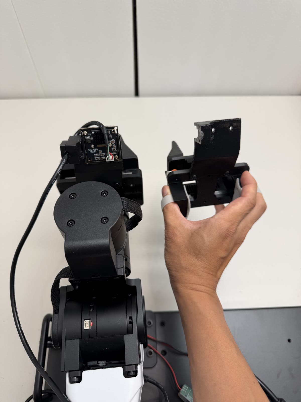 The YAM arm's linear gripper on the left, the YAM-UMI handheld device on the right, held in a hand. Same jaw geometry, same camera mount, same gripper tips.